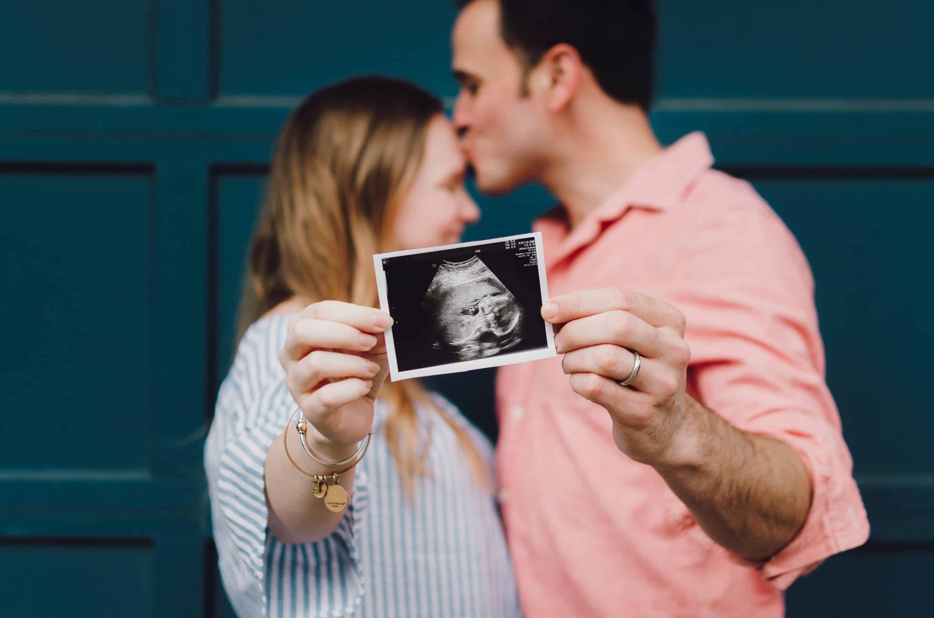 3 Life Events That Affect your Taxes. Picture of couple holding an ultrasound, while the man kisses the forehead of the women, taken by Kelly Sikkema.